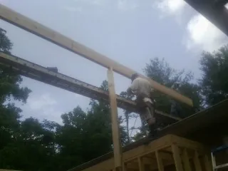 Carpenter setting a ridge beam over a new addition frame — Ice Dam Removal by Roofing Brothers in Suttons Bay