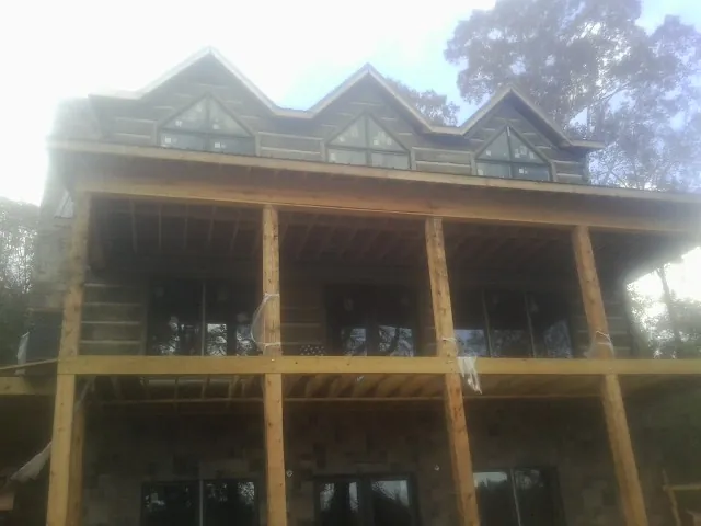 Dormers and porch framing on a large log home under construction — Roof Coating work by our crew in Suttons Bay