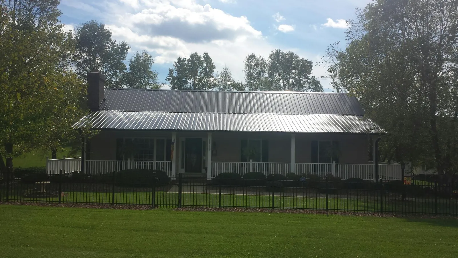 Gray metal roof on a brick ranch with a full width front porch — Gutter Guard Installation work by our crew in Suttons Bay