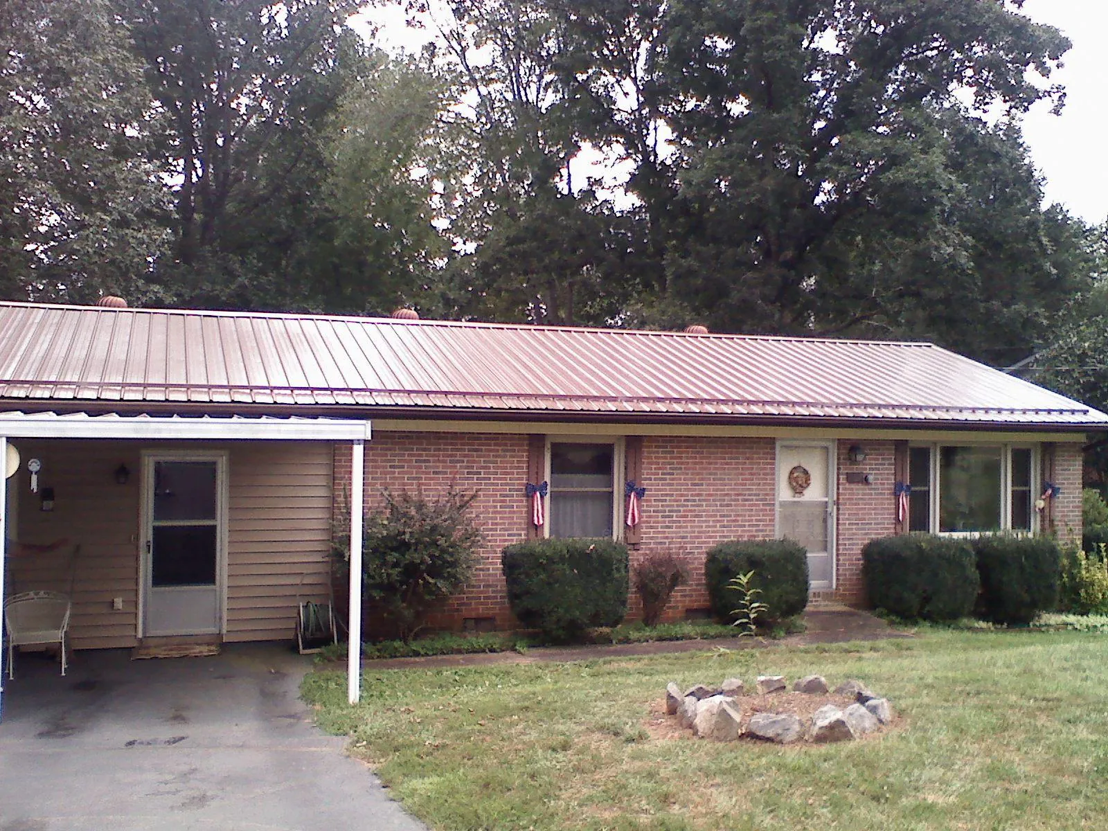 Bronze metal roof and carport on a brick ranch home — Roof Repair work by our crew in Suttons Bay