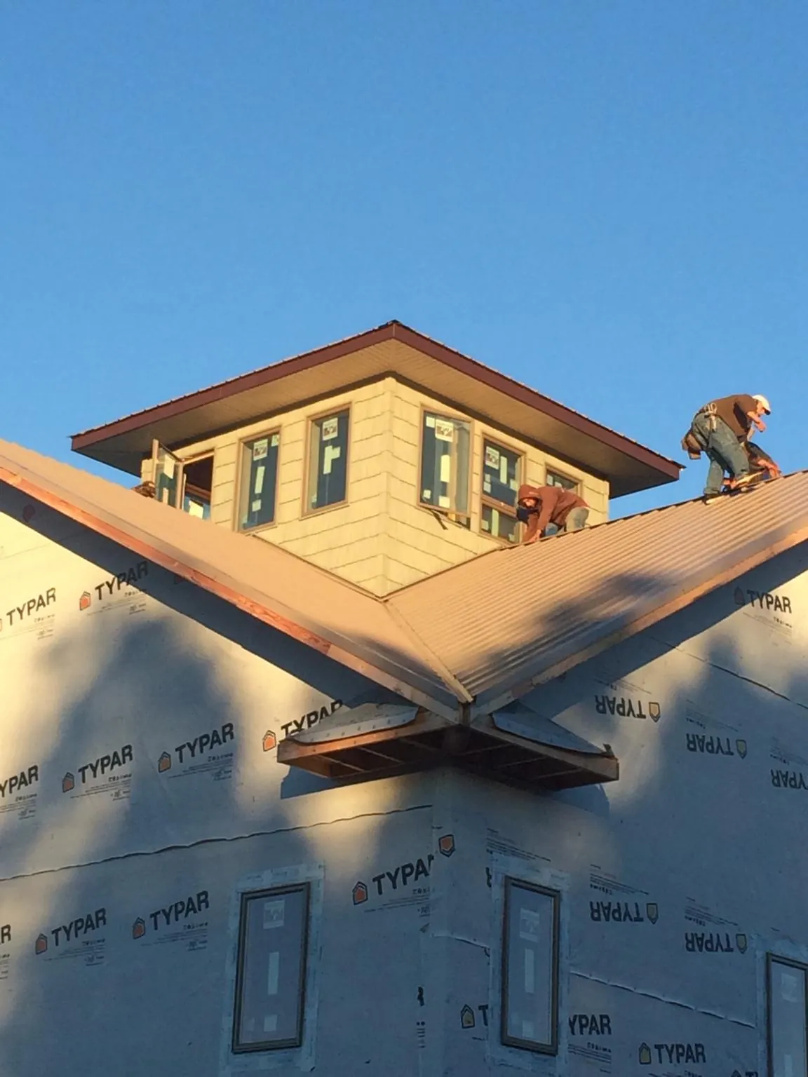 Roofers working around a rooftop cupola on a new metal roof at sunset — Roof Waterproofing in Suttons Bay by Roofing Brothers